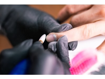 Close-up of manicurist woman removes gel shellac polish from client's nails using manicure